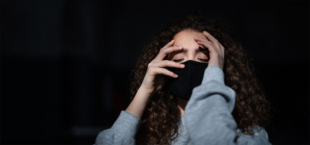 A portrait of depressed young woman indoors, covid-19 and mental health concept.